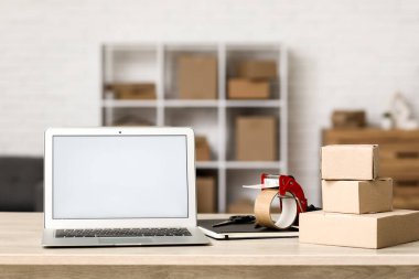 Boş dizüstü bilgisayar, ambalajlı bant ve paket kutuları depoda.