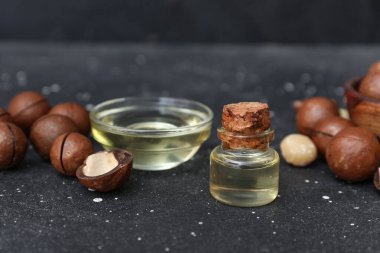 Siyah arka planda bir kase yağ ve fındık, yakın plan.