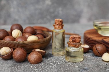 Arka planda Macadamia fındıkları olan yağ şişeleri, yakın plan.