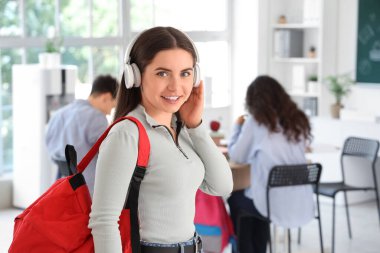 Sınıfta kulaklığı ve sırt çantası olan genç bir kız öğrenci var.