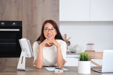 Genç Asyalı iş kadını mutfaktaki masada.