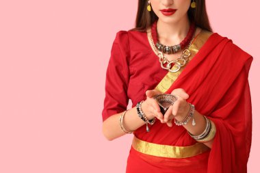 Pembe arka planda diya lambası olan, sarili güzel bir Hintli kadın, yakın plan.