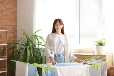 Çamaşır odasında temiz giysileri kurutucuya asan güzel bir genç kadın.