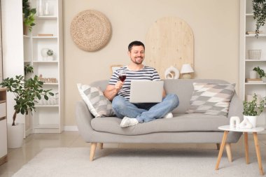 Şarabı olan yakışıklı adamın evdeki kanepede online randevusu var.