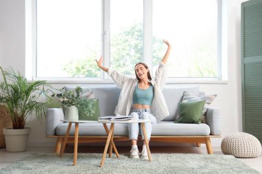 Oturma odasındaki gri kanepeye uzanan genç kadın.