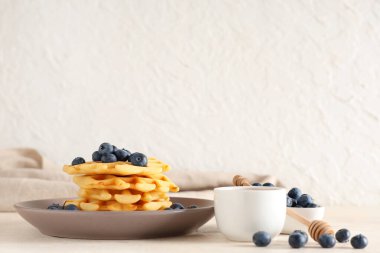 Lezzetli Belçika waffleları, tabakta yaban mersini ve beyaz arka planda bal.