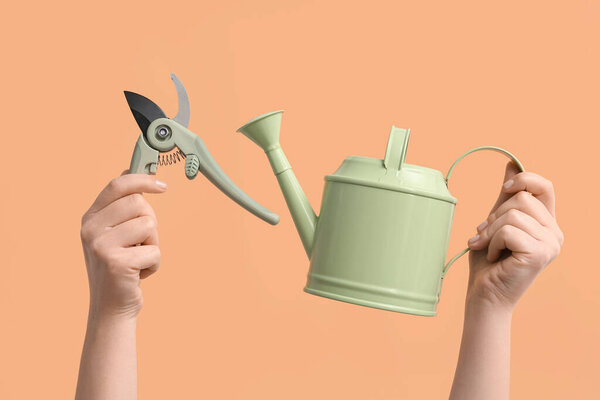 Руки женщины держат банку для полива и обрезку на бежевом фоне