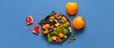 Mavi zemin üzerinde hurma olan lezzetli bir salata tabağı.