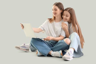 Dizüstü bilgisayarlı genç lezbiyen çift arka planda oturuyor.