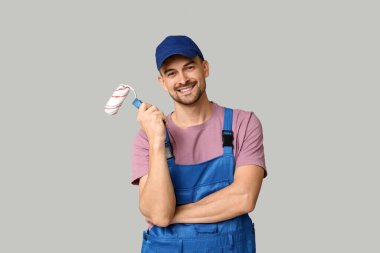 Gri arka planda boya silindiri olan erkek ressamın portresi