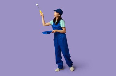 Pembe arka planda silindiri ve tepsisi olan Asyalı kadın ressam.