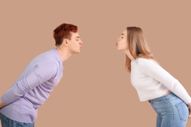 Kahverengi arka planda öpüşen mutlu genç çift