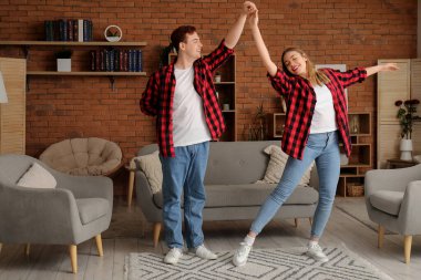 Mutlu genç çift evde dans ediyor.