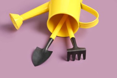 Mor arka planda bahçe tırmığı ve kürekle teneke sulama.