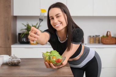 Mutfakta bir kase taze salatası olan genç ve güzel bir kadın. Kilo verme konsepti