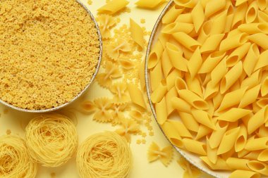 Bej arka planda farklı türde pişmemiş makarna içeren kaseler.