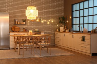 Parlayan lambaları, beyaz tezgahları, buzdolabı ve akşam masası olan şık bir mutfak.