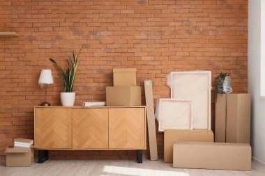 Mobilyalar, ev bitkisi ve karton kutular kahverengi tuğla duvarın yanında. Taşınma konsepti