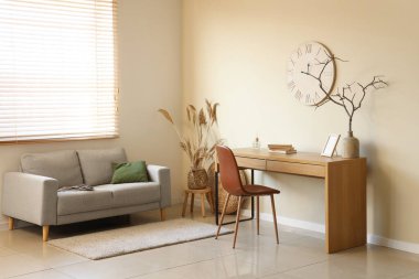 Kanepesi, çalışma yeri ve bej duvarlı saati olan şık bir oturma odası.