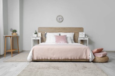 Beyaz duvarında yatak, yastık ve saat olan şık bir yatak odası.