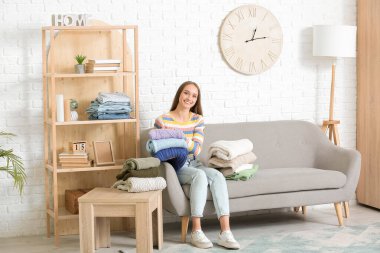 Evdeki kanepede oturan süveter yığınıyla genç bir kadın.