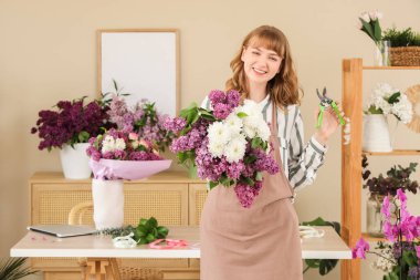 Çiçekçide çiçek buketi, leylak ve kasımpatı tutan kadın.