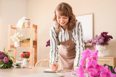 Çiçekçide çalışan defterli bir kadın çiçekçi.