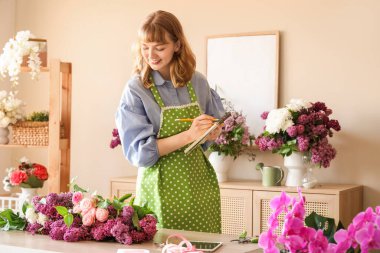Çiçekçide çalışan defterli bir kadın çiçekçi.