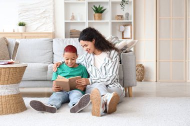 Annesi evde kitap okuyan küçük bir Afro-Amerikalı çocuk.