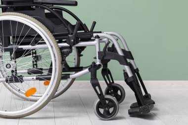 Yeşil duvarın yanındaki boş tekerlekli sandalye, yakın plan.