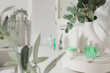 Okaliptüs dallı vazo ve makyaj malzemeleri soyunma odasındaki masada.