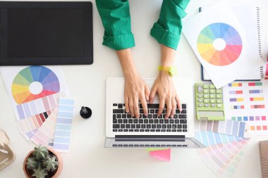 Grafik tasarımcısı masadaki dizüstü bilgisayarla çalışıyor, üst görünüm