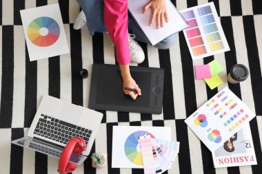 Ofisteki halı üzerinde tabletle çalışan kadın grafik tasarımcısı, üst görünüm