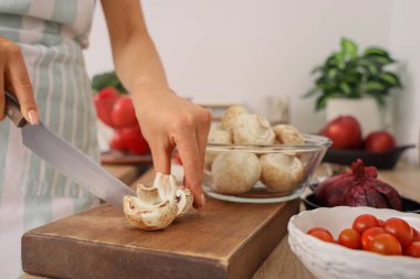 Mutfakta yemek pişirme kursunu kaydederken mantar kesen genç bir kadın, yakın plan.