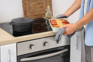 Mutfakta fırının yanında elmalı turtayla yemek pişiren genç adam, yakın plan.