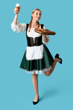 Güzel mutlu Ekim Festivali garsonu, birası ve mavi arka planda geleneksel yemekleri var.