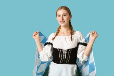 Mavi arka planda Bavyera bayrağıyla güzel mutlu bir Ekim Festivali garsonu.