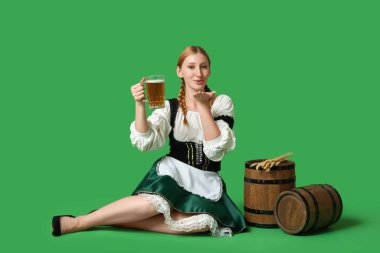 Güzel mutlu Ekim Festivali garsonu varilleri ve yeşil arka planda öpüşen bir kupa birayla