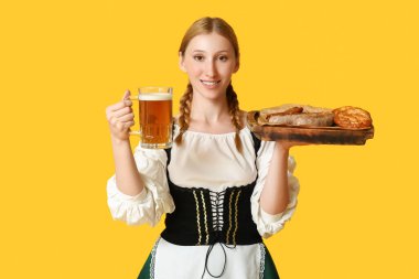 Güzel mutlu Ekim Festivali garsonu, birası ve sarı arka planda geleneksel yemekleri var.