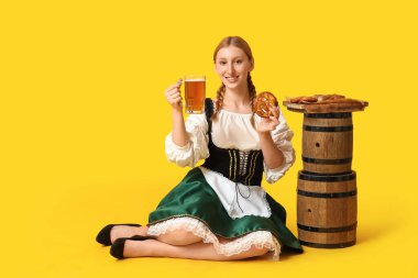 Güzel mutlu Ekim Festivali garsonu bira fıçıları ve sarı arka planda oturan geleneksel yemek tabağıyla