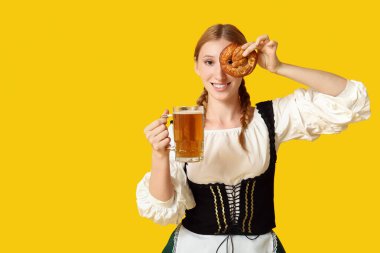 Güzel mutlu Ekim Festivali garsonu. Sarı arka planda bir kupa bira ve krakerle.