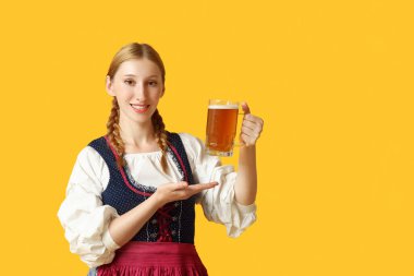 Güzel mutlu Ekim Festivali garsonu sarı arka plandaki bira kupasını işaret ediyor.