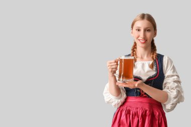 Gri arka planda bir kupa birayla güzel mutlu Ekim Festivali garsonu.