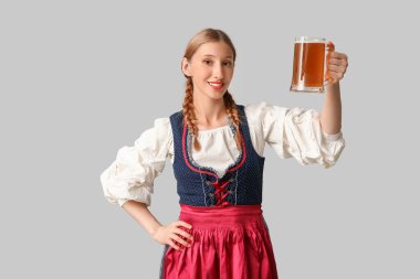 Gri arka planda bir kupa birayla güzel mutlu Ekim Festivali garsonu.