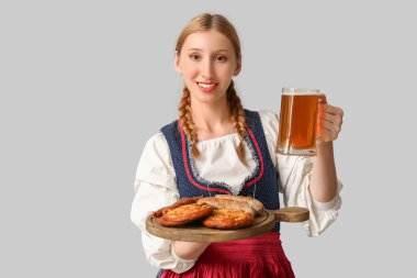 Güzel mutlu Ekim Festivali garsonu. Bira ve gri arka planda geleneksel yiyeceklerle dolu.