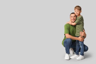 Mutlu baba, gri arka planda küçük oğluna sarılıyor.