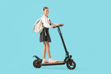 Mavi arka planda elektrikli scooter kullanan kulaklıklı tatlı bir kız öğrenci.