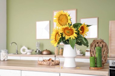 Şık mutfaktaki tezgahın üzerinde bir buket güzel ayçiçeği olan vazo.