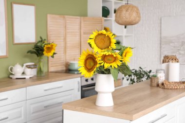 Beyaz tezgahları ve güzel ayçiçekleri olan şık bir mutfak.