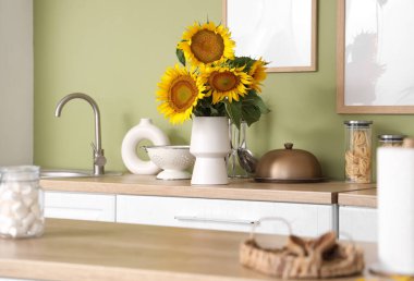 Beyaz tezgahları ve güzel ayçiçekleri olan şık bir mutfak.